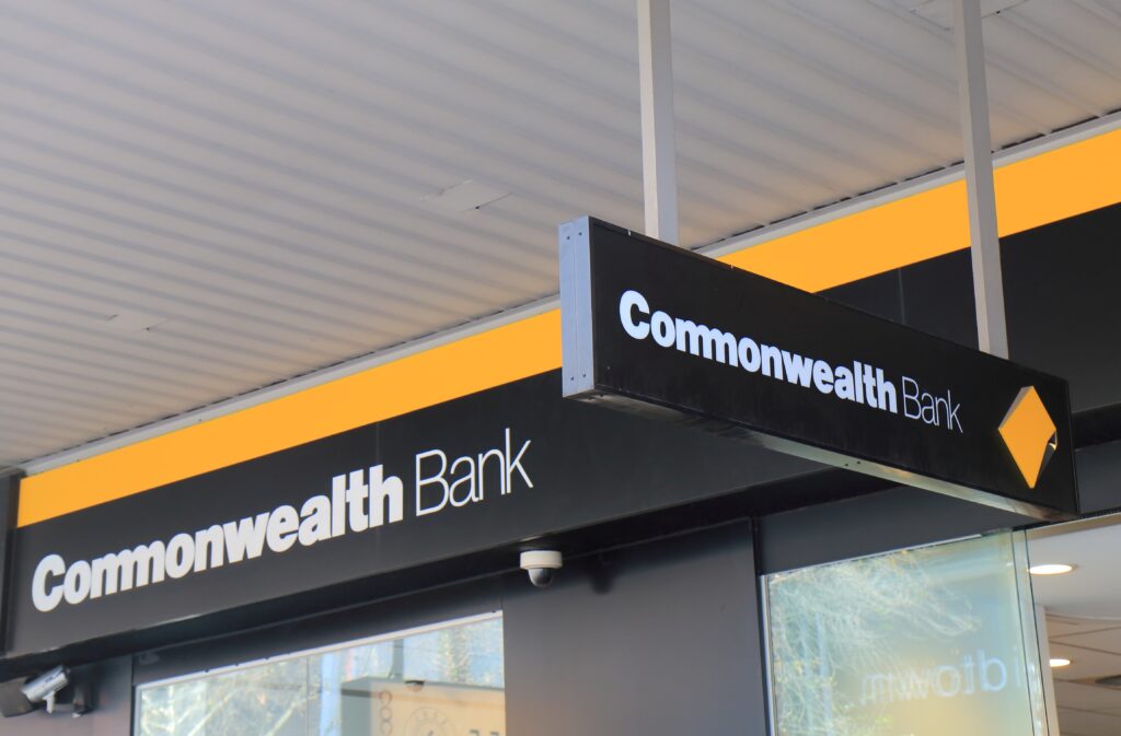 Fachada de una sucursal del Commonwealth Bank of Australia con logotipo y letrero visibles.