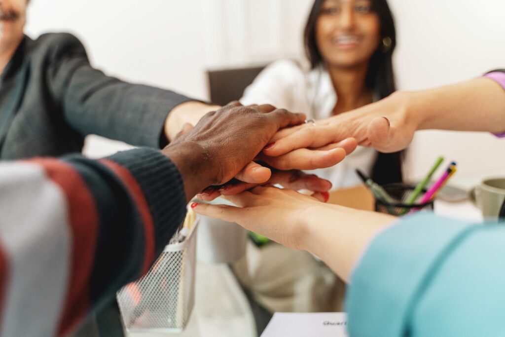 Manos unidas de un grupo diverso simbolizando colaboración, compromiso y cultura organizacional orientada al crecimiento sostenible