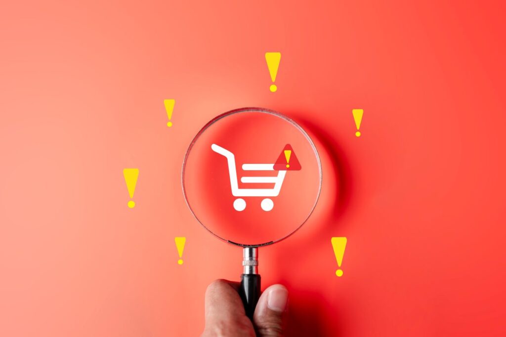 Lupa sobre carrito de compras con signos de alerta, símbolo de promociones consumidor y desconfianza económica en Estados Unidos.