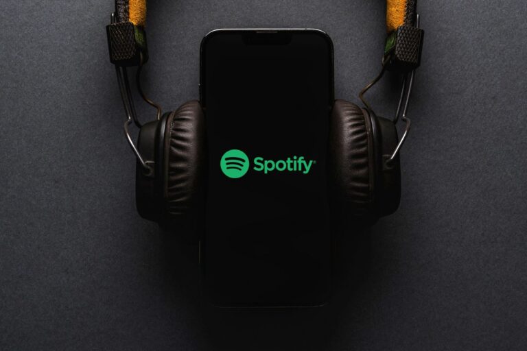 Teléfono con logo de Spotify y audífonos, ilustrando el aumento de precios y nuevas funciones premium para impulsar crecimiento