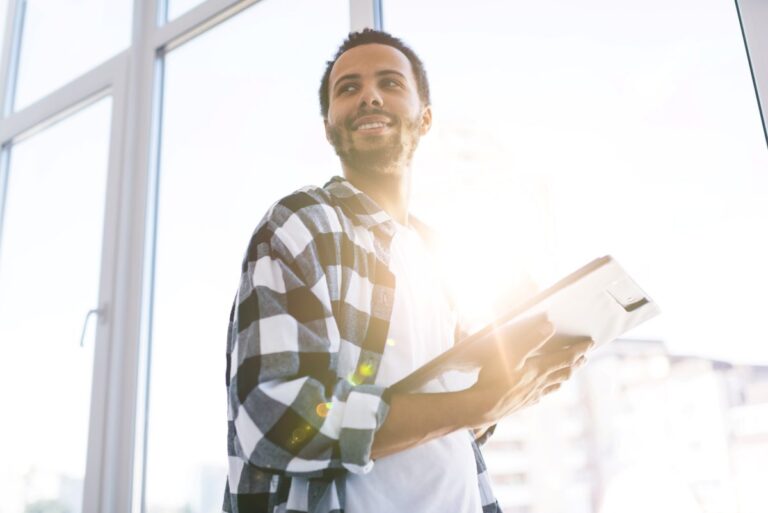 Hombre joven sonriente con tableta en manos simboliza startups españolas que lideran sostenibilidad e innovación empresarial.