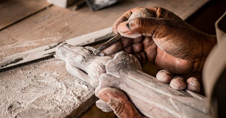 Una persona sostiene en su mano una escultura de madera.