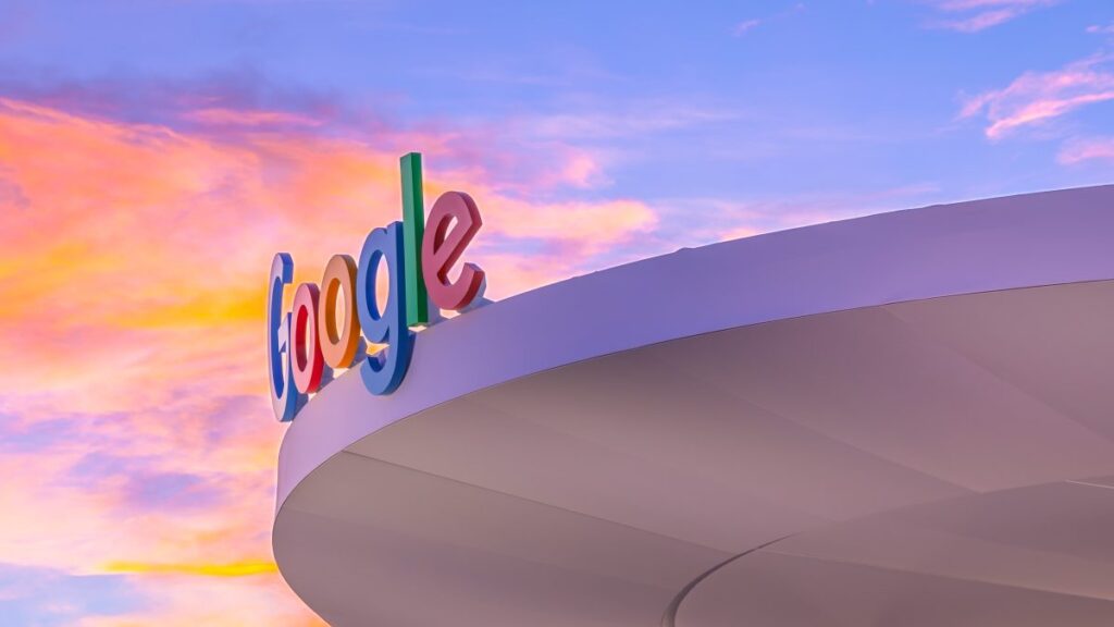 Logotipo de Google en edificio corporativo con cielo colorido al atardecer, símbolo de innovación y cultura empresarial