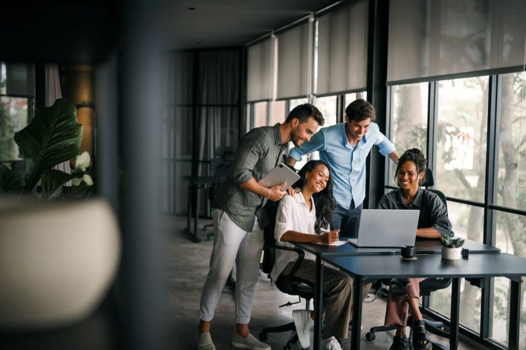 Equipo diverso de profesionales trabajando en una oficina moderna con luz natural, reflejando confianza, propósito y liderazgo colaborativo. Refleja cultura empresarial.
