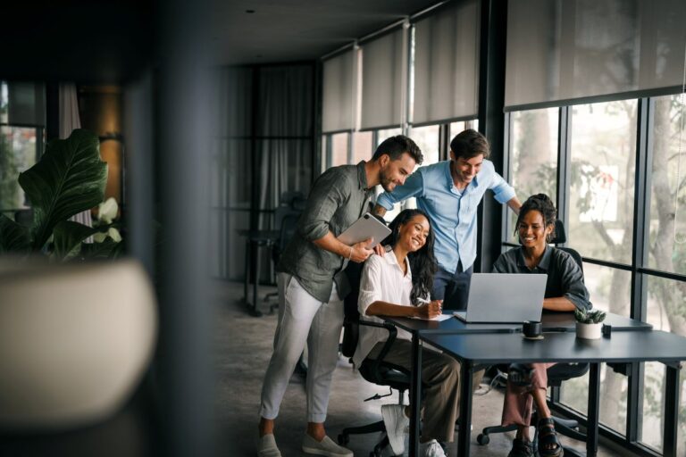 Equipo diverso de profesionales trabajando en una oficina moderna con luz natural, reflejando confianza, propósito y liderazgo colaborativo. Refleja cultura empresarial.