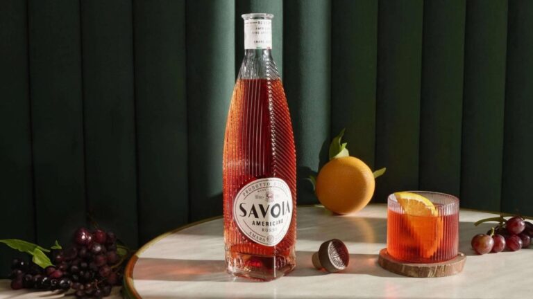 Botella de Savoia Americano Rosso sobre mesa elegante con copa de aperitivo y frutas frescas, en estilo fotográfico aspiracional y profesional.