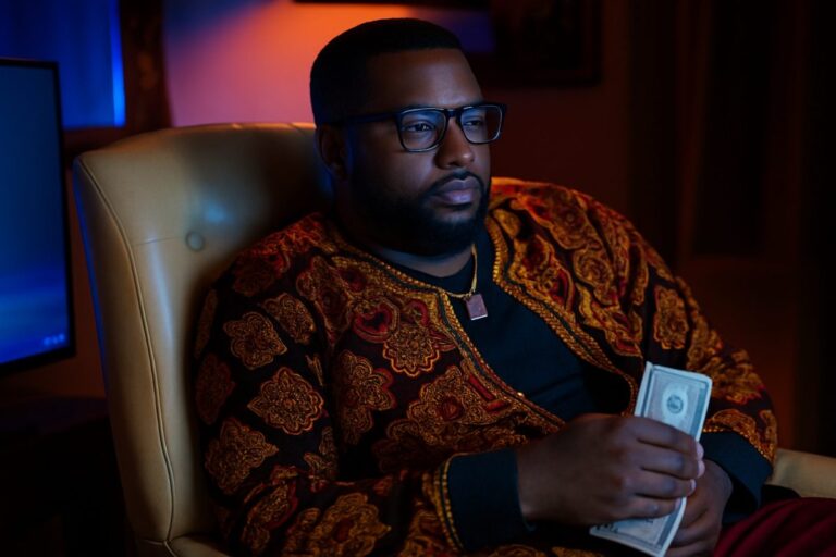 Persona pensativa frente a pantallas en ambiente cálido, simboliza el reto de crear GTA 6