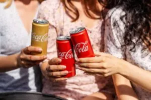 Personas celebrando con latas de Coca-Cola, símbolo de diversidad y empleo inclusivo