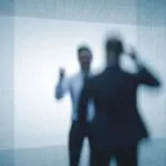 Imagen editorial fotorealista de dos figuras humanas en conflicto dentro de un entorno de oficina moderna, simbolizando la violencia en el trabajo