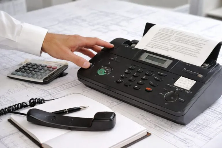 Imagen editorial de una oficina alemana enviando documentos por fax, representando su cultura empresarial tradicional