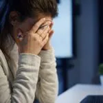 Mujer con expresión de ansiedad en su lugar de trabajo, reflejo del estrés financiero laboral