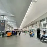 Pantalla de aeropuerto con vuelos cancelados y referencia a caída bursátil en aerolíneas en 2026