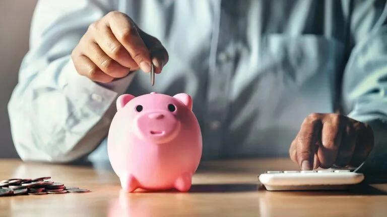 Persona revisando presupuesto y gastos para mejorar sus finanzas personales con libreta, calculadora y dinero en mesa