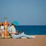 Trabajador en la playa revisando su celular con expresión concentrada, símbolo de no desconectarse del trabajo