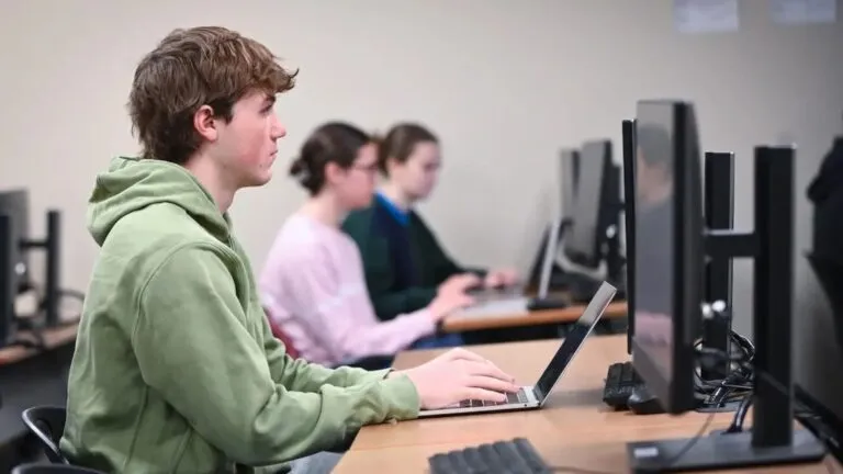 Estudiantes universitarios trabajando con computadoras y herramientas de inteligencia artificial en campus moderno