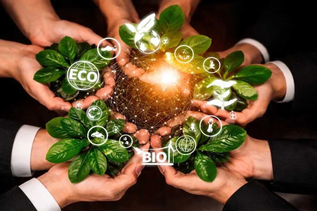 Manos sosteniendo hojas verdes con íconos de sostenibilidad ambiental y social, símbolo de sostenibilidad empresarial