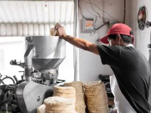 Tortillería tradicional y producción industrial representando la industria de la tortilla en México y su expansión global