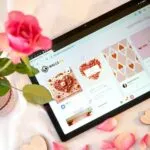 Pareja intercambiando regalos de tecnología como un Kindle y auriculares, en ambiente cálido de San Valentín