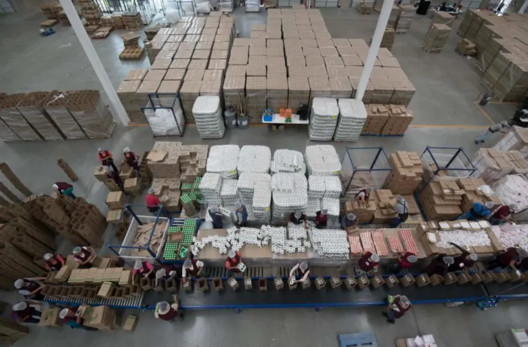 Centro logístico de La Cosmopolitana con personal supervisando almacenamiento y distribución de alimentos para instituciones.