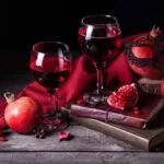 Botella de vino de granada artesanal junto a frutas frescas, en una composición representativa de la producción de Chilcuautla, Hidalgo.