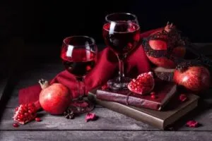 Botella de vino de granada artesanal junto a frutas frescas, en una composición representativa de la producción de Chilcuautla, Hidalgo.