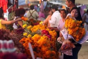 Compras de Día de Muertos con pan tradicional, flores de cempasúchil, veladoras y decoraciones disponibles en un negocio mexicano.