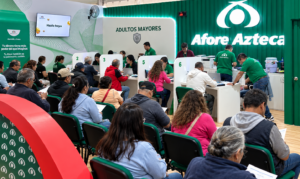 Personal de Afore Azteca brinda atención a trabajadores en un módulo de servicios, con asistentes sentados frente a los escritorios.
